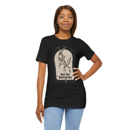 a beautiful black woman with straight dark brown hair wearing blue jeans and a gothic black tshirt with a ghost mantis illustration that says "eat the patriarchy"