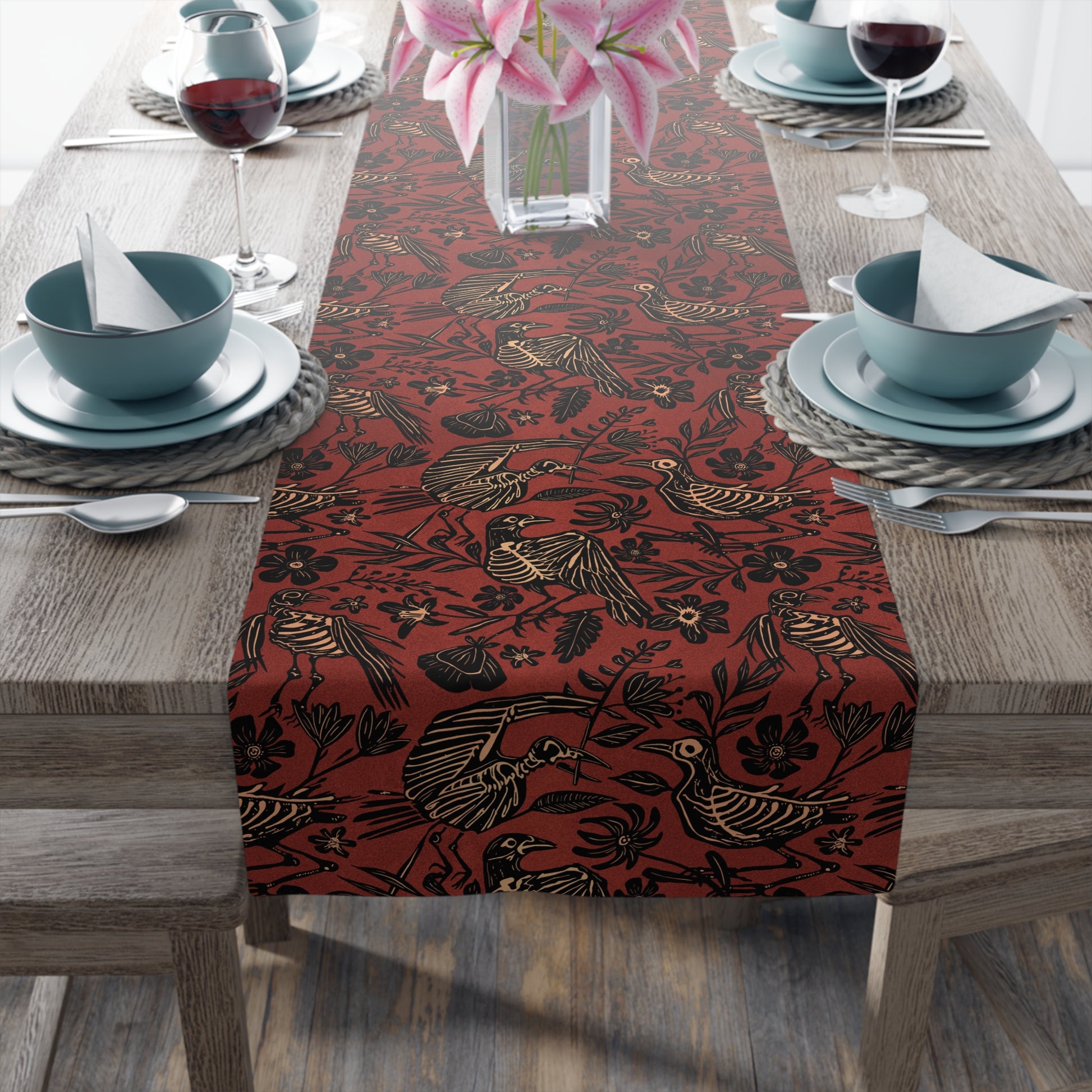 macabre autumn folk art floral bird skeleton table runner in rust red orange on an elegant table with ceramic dishes and a vase of lillies