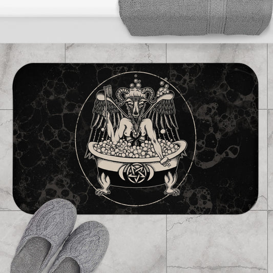 a darkly funny satanic pun "bathomet "bath mat featuring baphomet in a claw foot bathtub with a gothic black background. on a gray tile floor outside of a  shower with gray slippers sitting on top.