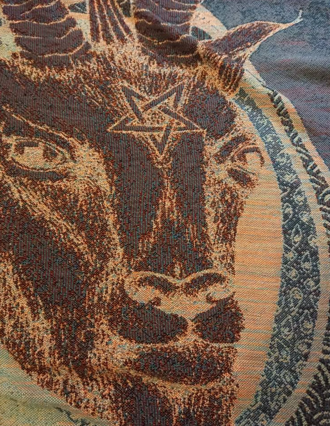 A multicolored woven blanket with a Saint Baphomet artwork.