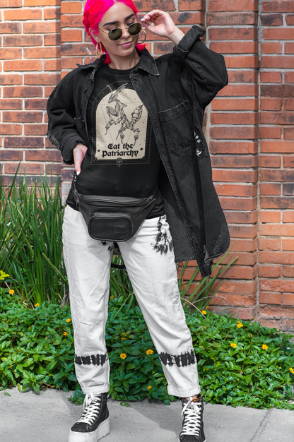 a fashionable young adult woman with neon pink hair wearing a punk rock black denim jacket, platform converse shoes, a leather belt pouch, stylish sunglasses, and a gothic black thirt with a witchy feminist praying mantis illustration that says "eat the patriarchy"