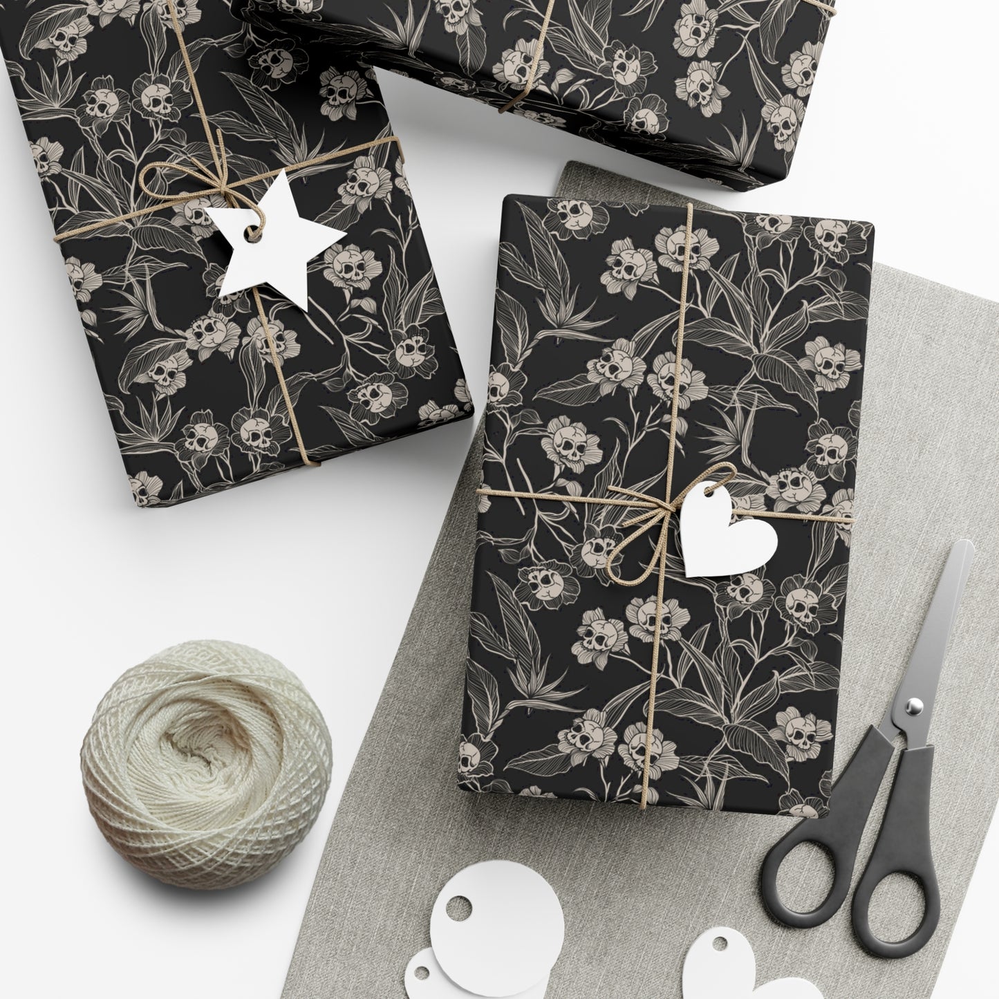 Black gothic floral-patterned gift wrap with decorative tags and scissors on a white surface