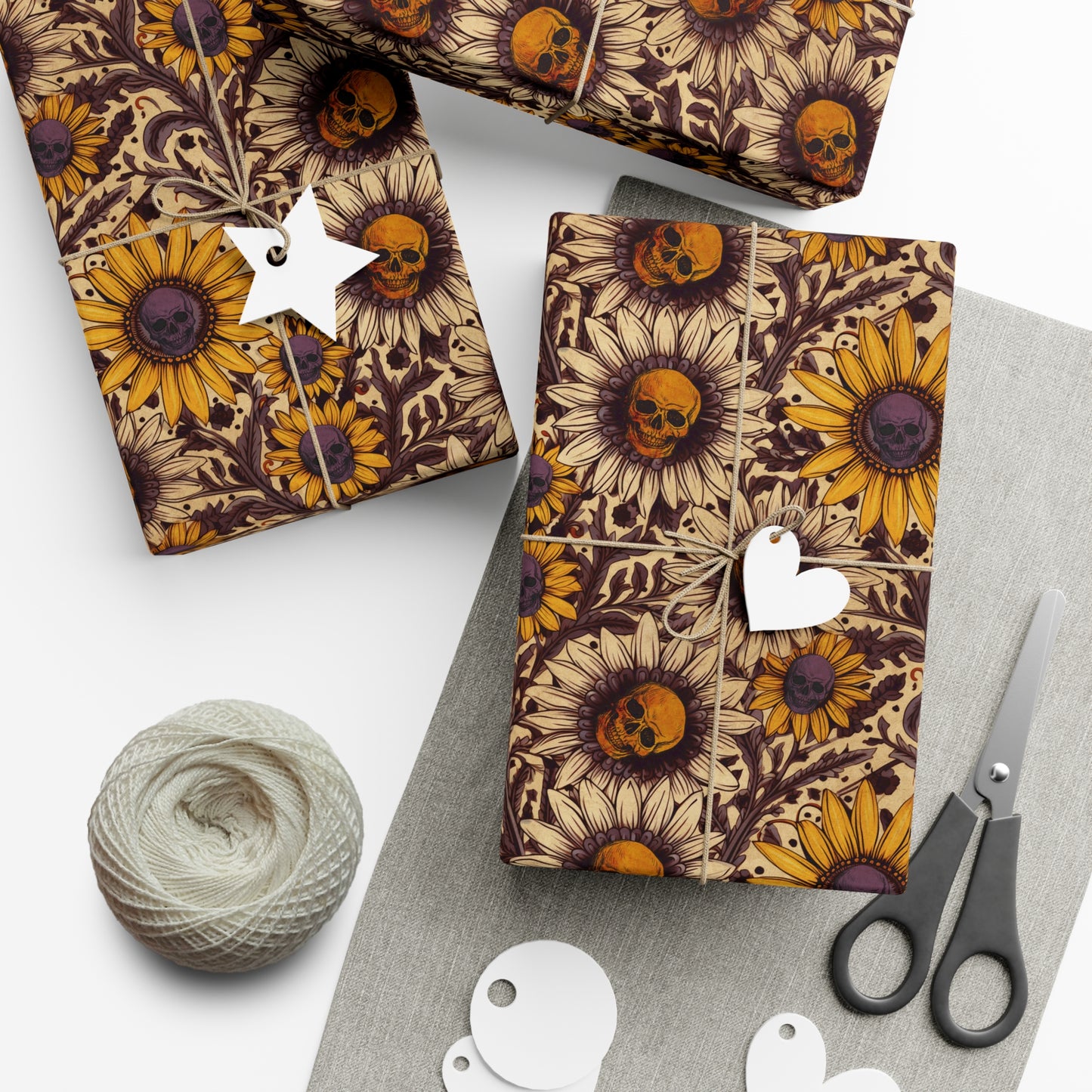 witchy Gift wrap with sunflower and skull pattern on a white surface with yarn and scissors.