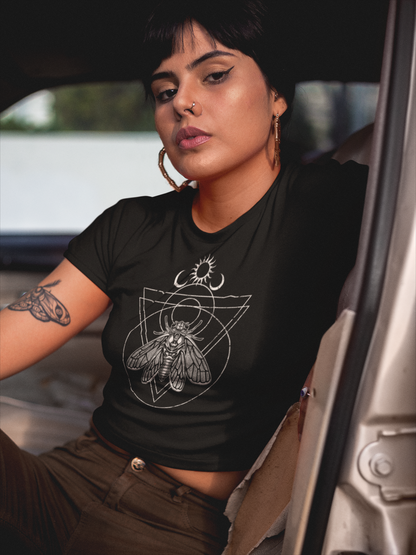 Woman wearing a black t-shirt with a witchy cicada design, sitting inside a vehicle.