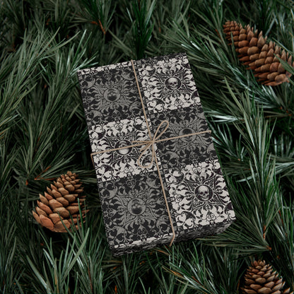 Gift box with skull pattern wrapped in paper and tied with string, surrounded by pine branches and pinecones.