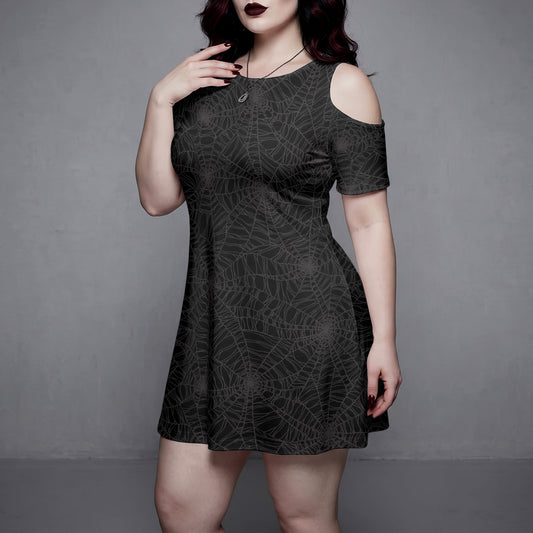 Goth Woman wearing a black dress with spider web pattern against a gray background