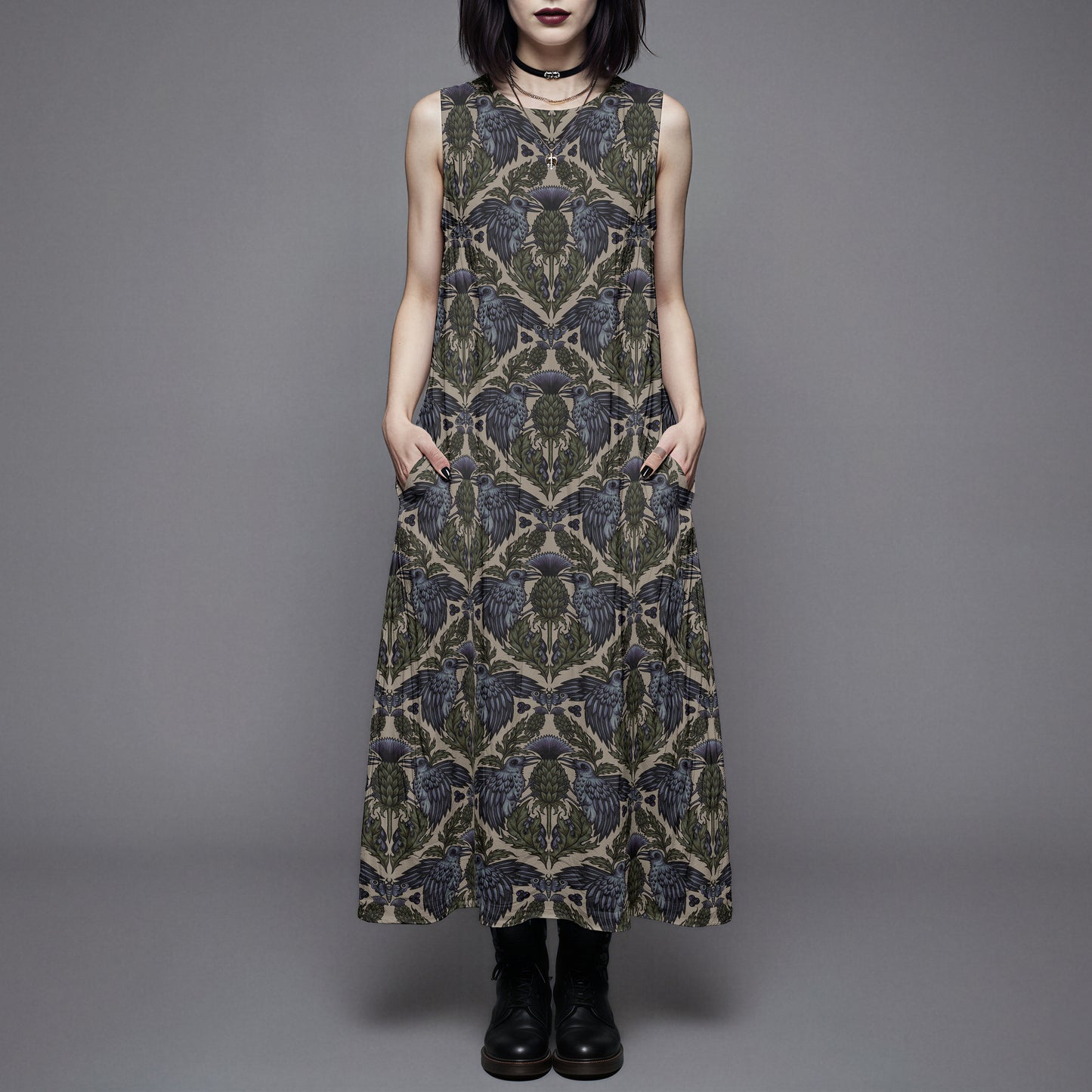goth woman wearing a witchy raven thistle cotton dress with pockets against a gray background