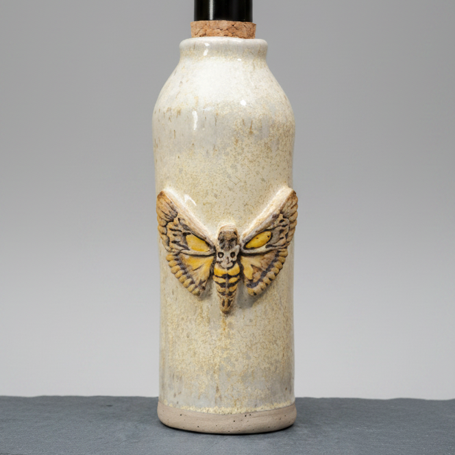 Ceramic bottle with a moth design on a gray background