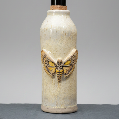 Ceramic bottle with a moth design on a gray background