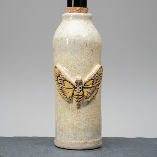 Ceramic bottle with a moth design on a gray background