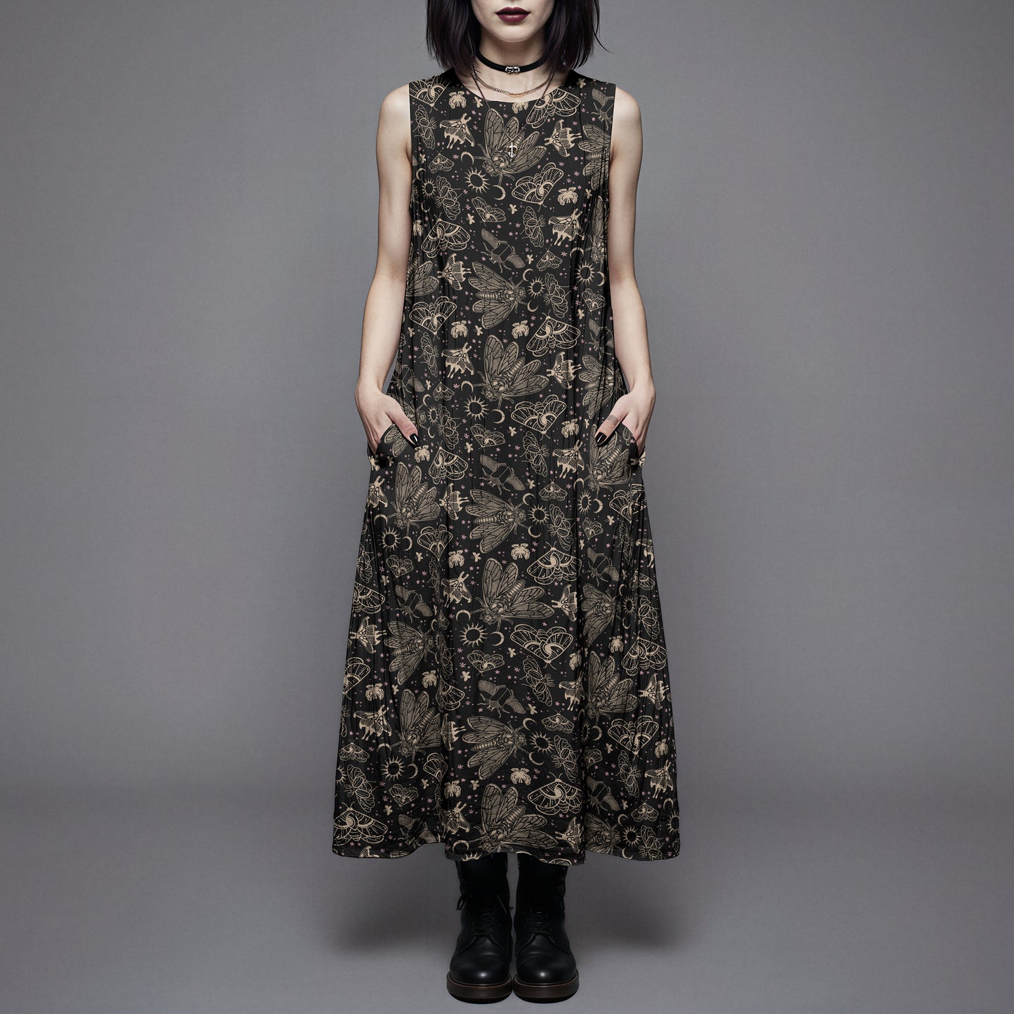 Woman wearing a long black dress with a witchy moth and cicada print against a gray background