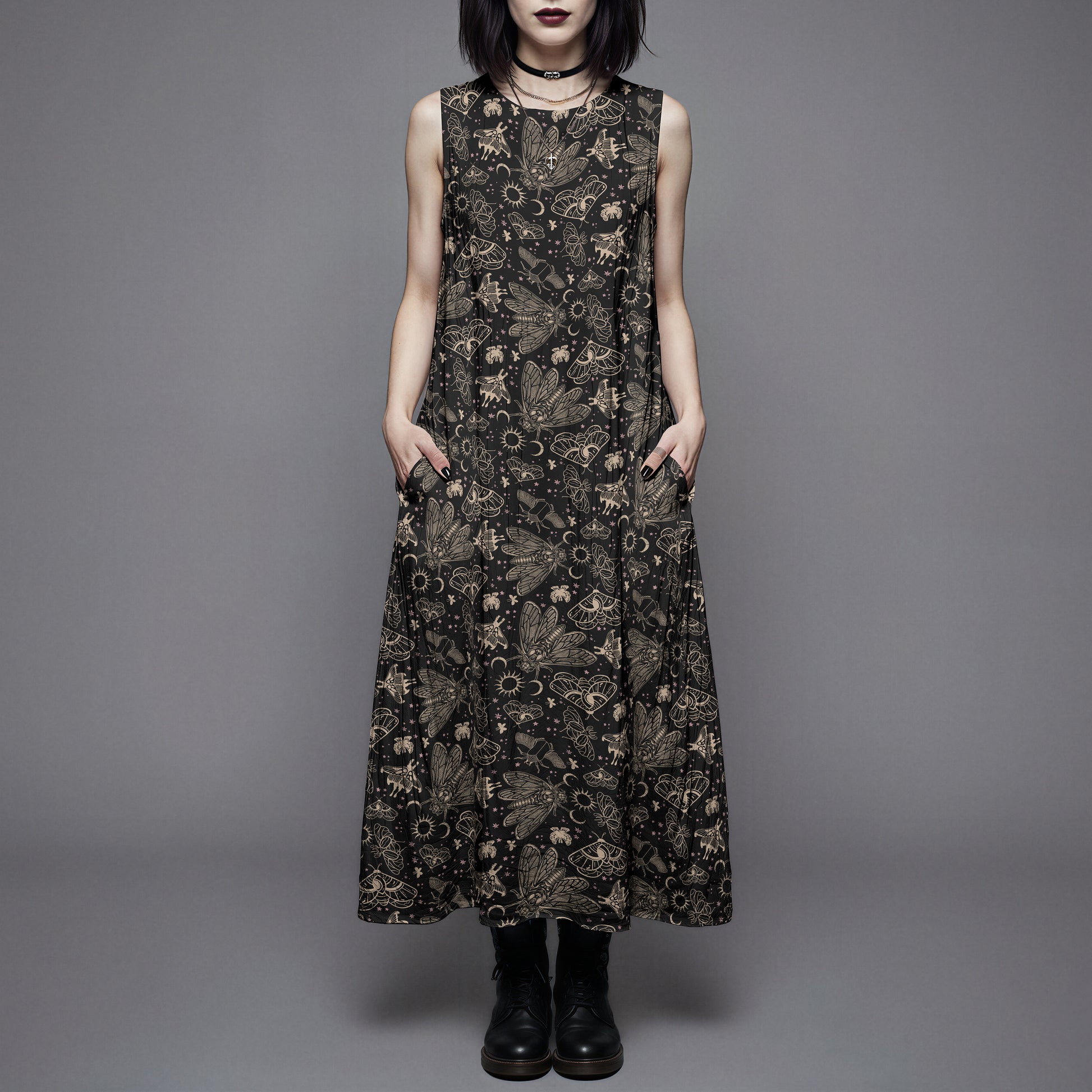 Woman wearing a long black dress with a witchy moth and cicada print against a gray background