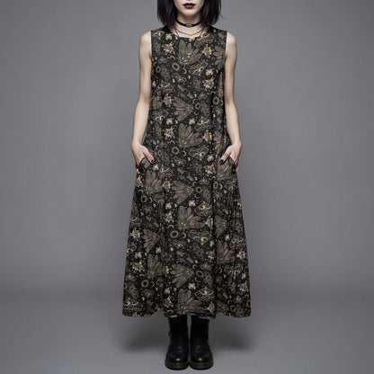 Woman wearing a long black dress with a witchy moth and cicada print against a gray background