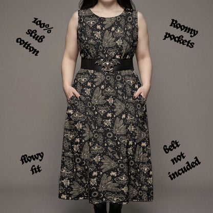 goth woman in a Long black dress with witchy cicada and moth print on a plain background with text indicating fabric details.