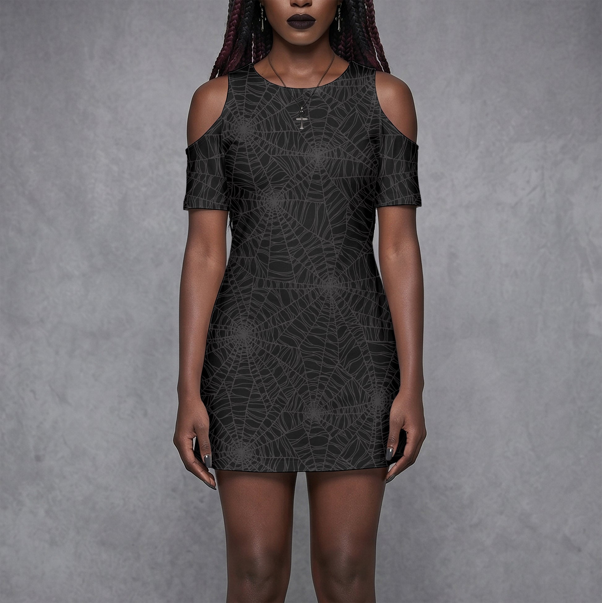 Goth Woman wearing a black spider web cold shoulder dress with spooky vibes against a gray background