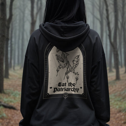 gothic woman wearing a black hoodie that says eat the patriarchy with an illustration of a praying mantis in a forest