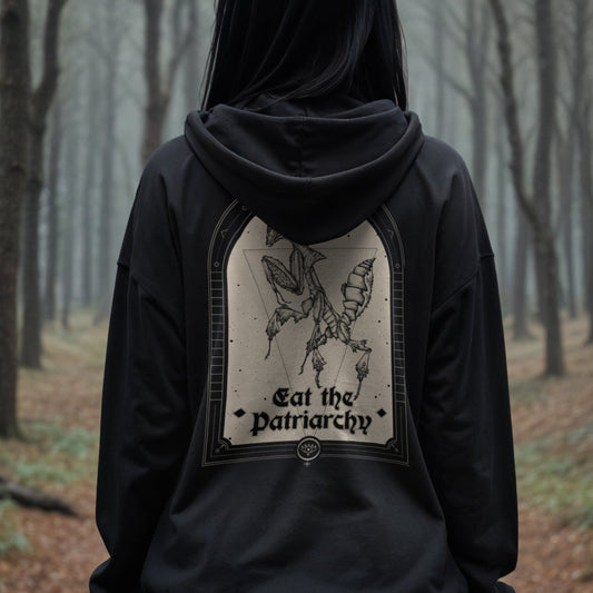 gothic woman wearing a black hoodie that says eat the patriarchy with an illustration of a praying mantis in a forest