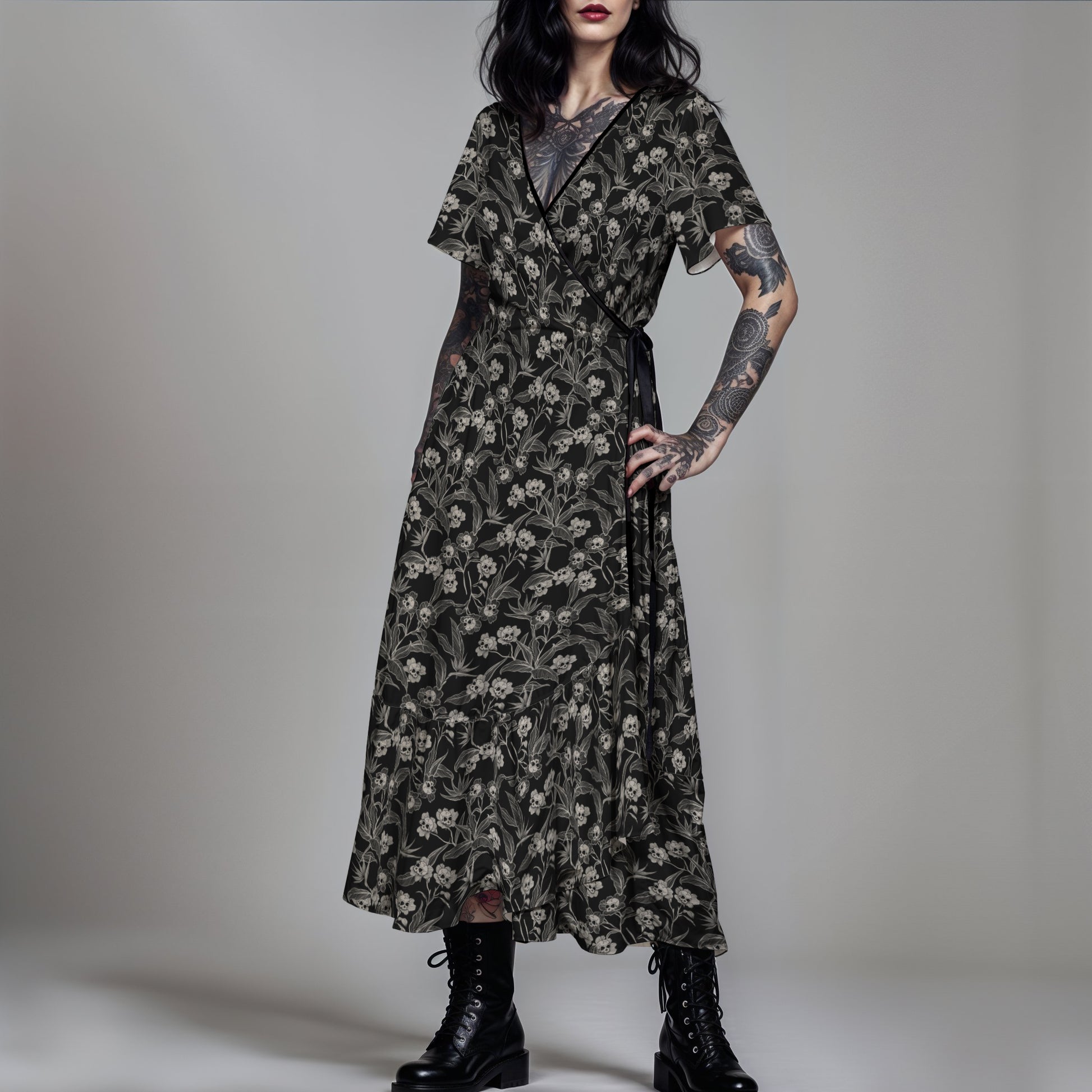 gothic woman wearing a dark floral skull dress with tattoos on arms against a gray background