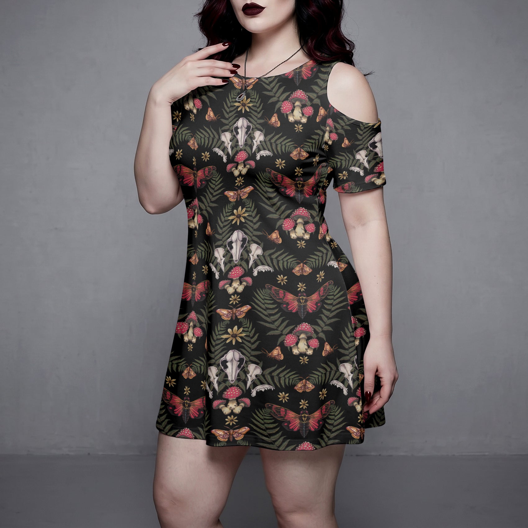plus sized goth Woman wearing a witchy forest patterned dress against a gray background