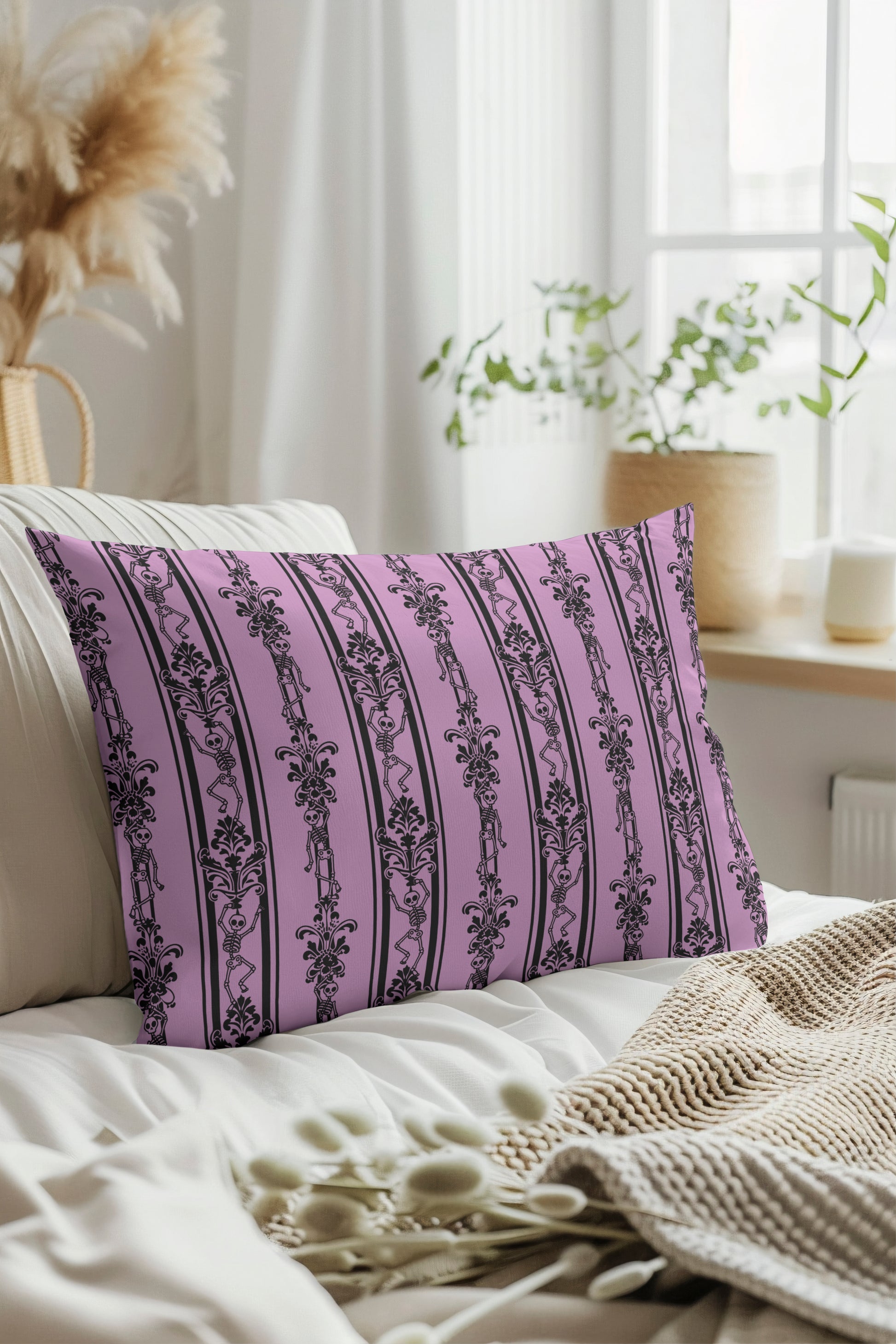 Decorative pink pillow with black skeleton patterns on a white couch in a bright room.