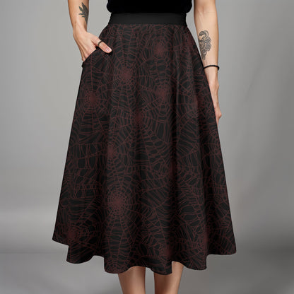 Dark burgundy and black spider web midi skirt skirt worn by a goth woman with tattoos on a gray background