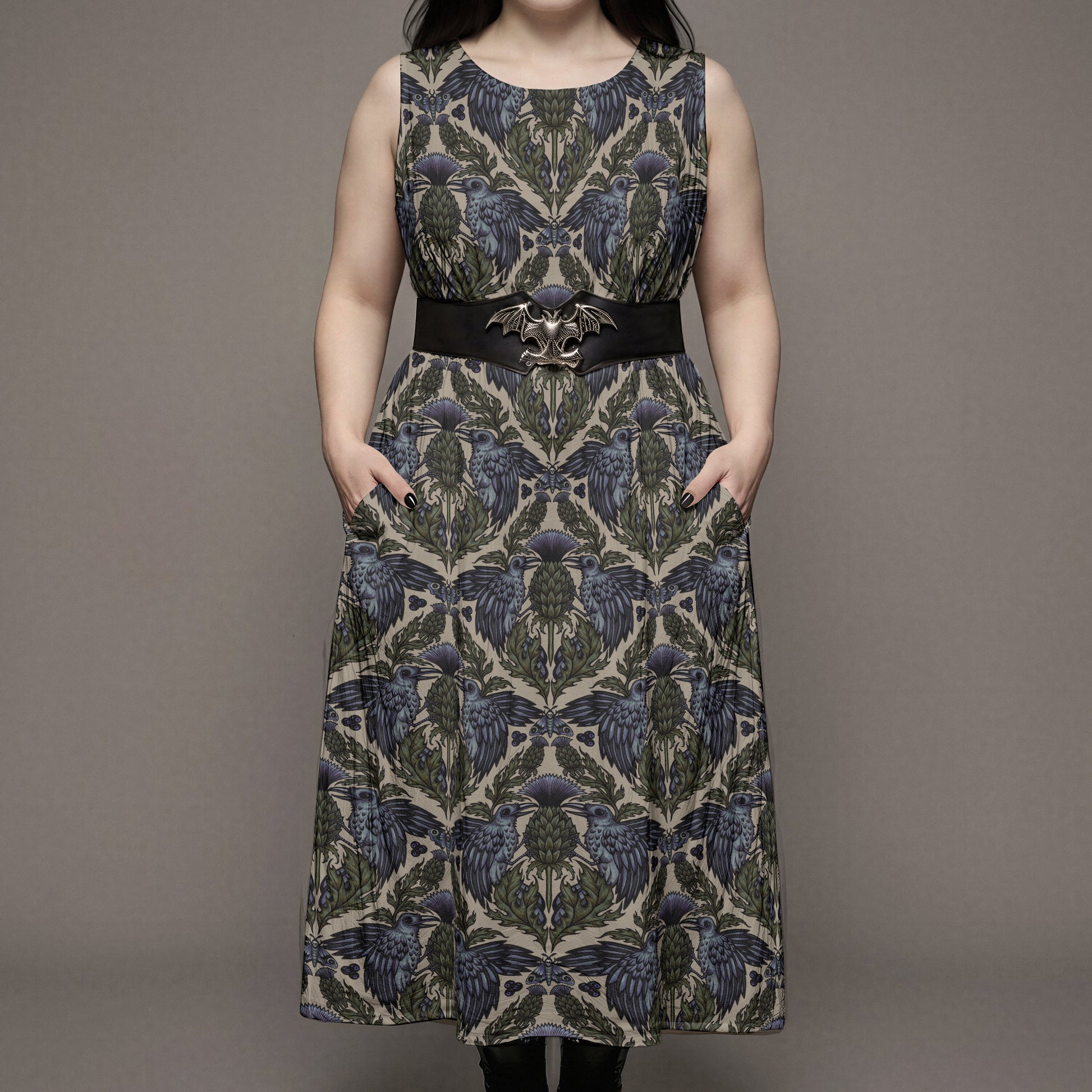 plus sized goth woman wearing a witchy raven thistle patterned dress with a belt on a plain background