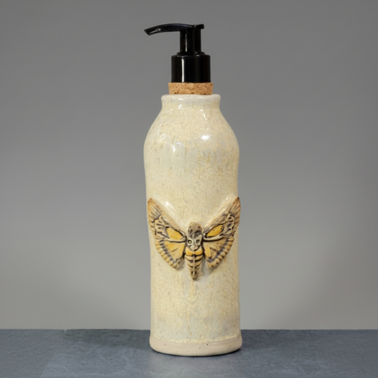 Ceramic bottle with moth design and pump on a gray background