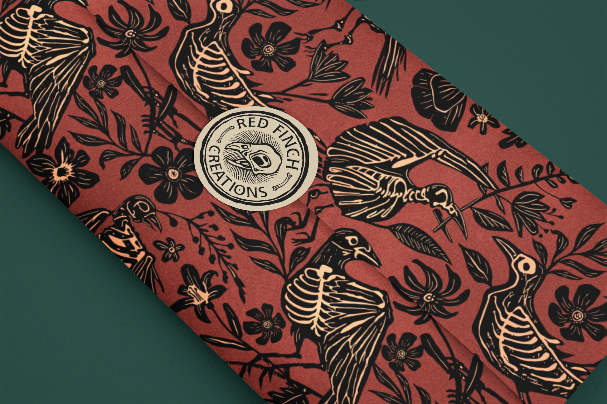 witchy wrapping paper with red background and black skeleton-like bird and floral pattern, featuring 'Red Finch Creations' logo.