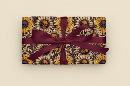 Gift with gothic sunflower and skull pattern wrapping paper with a purple ribbon on a beige background