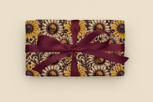 Gift with gothic sunflower and skull pattern wrapping paper with a purple ribbon on a beige background