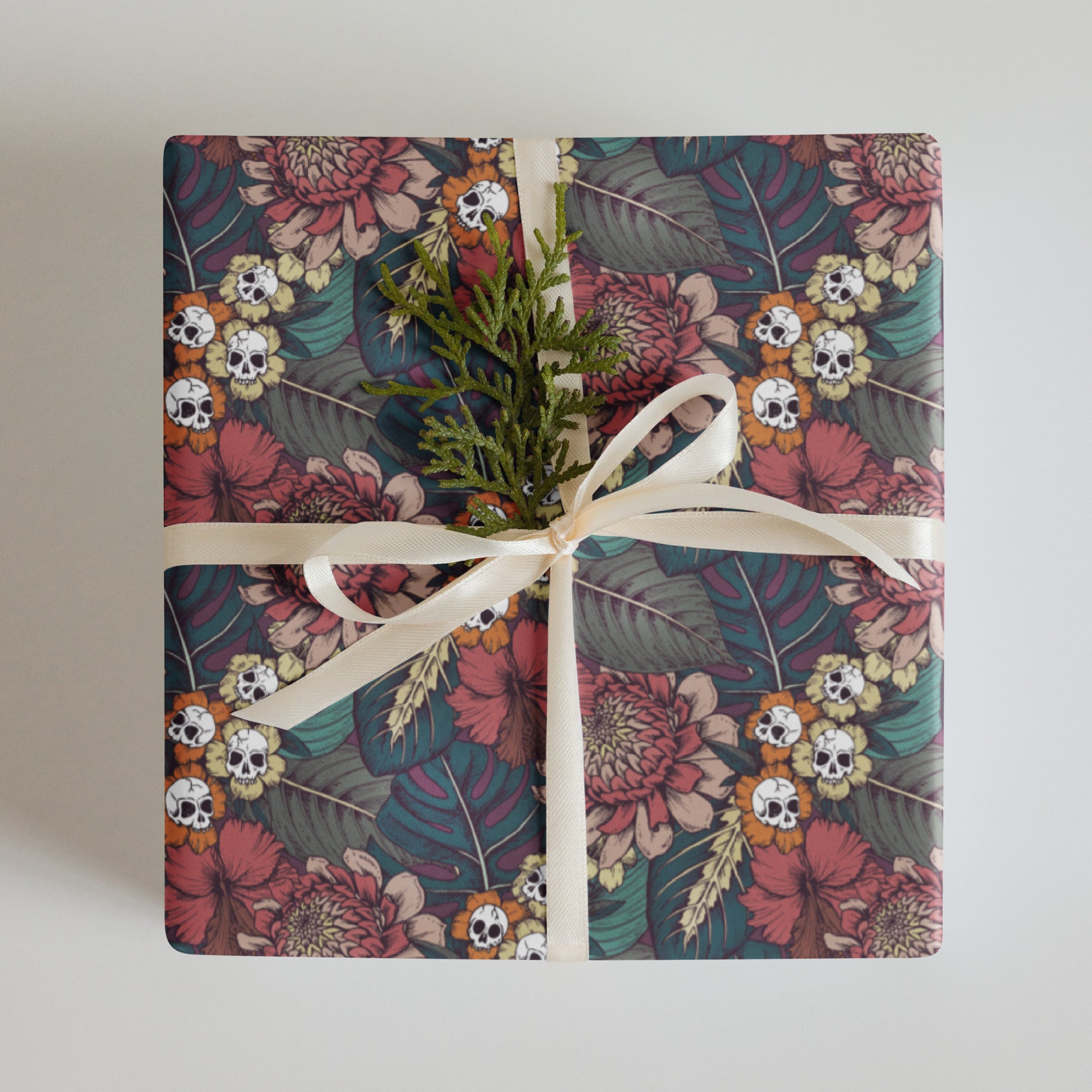 Gift wrapped in floral skull paper with a white ribbon on a light background