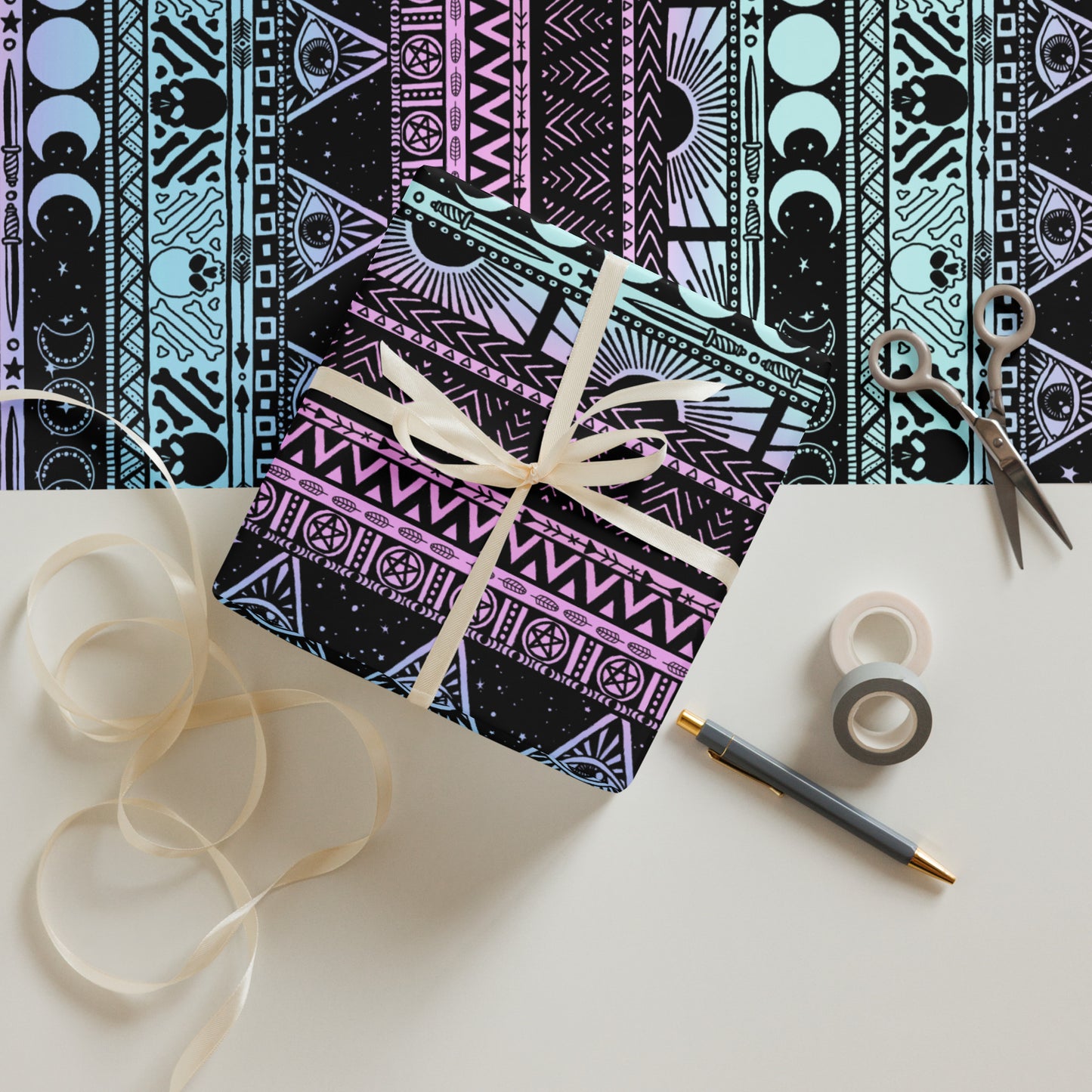 Decorative box with a witchy pastel patterned design, ribbon, scissors, and tape on a white surface.
