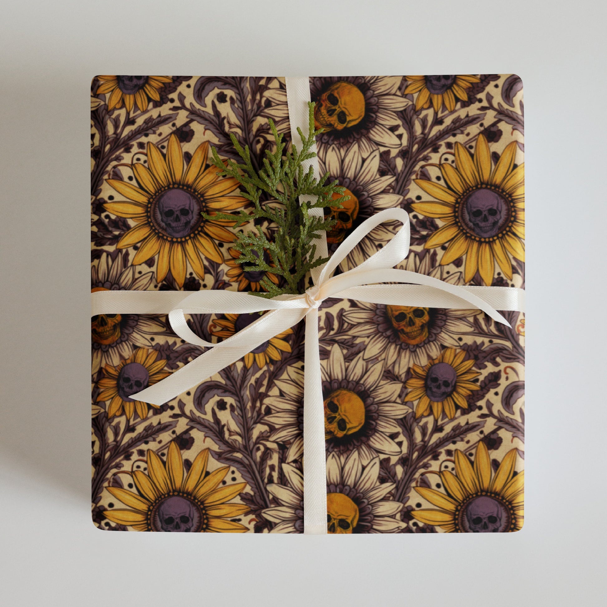 Gift wrapped in paper with sunflower and skull design on a plain background