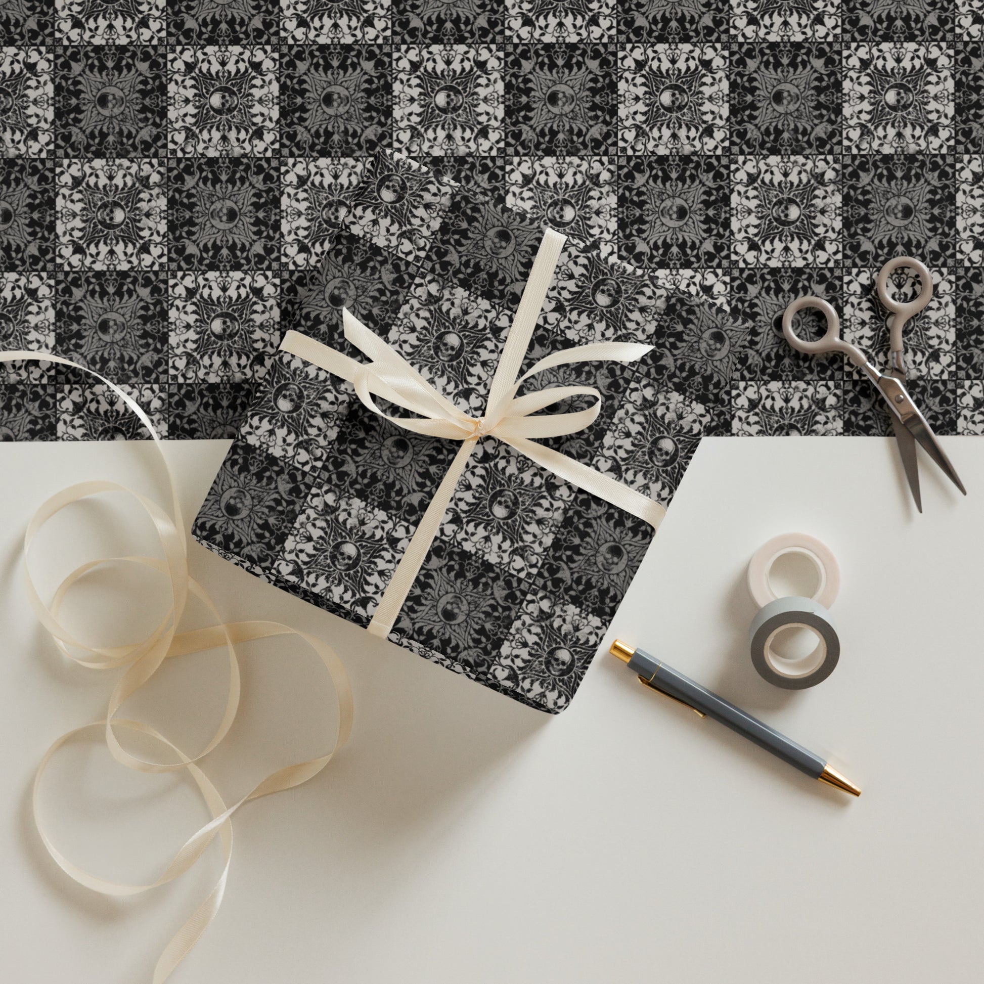 Gift box with decorative ribbon on a patterned surface with scissors and tape.