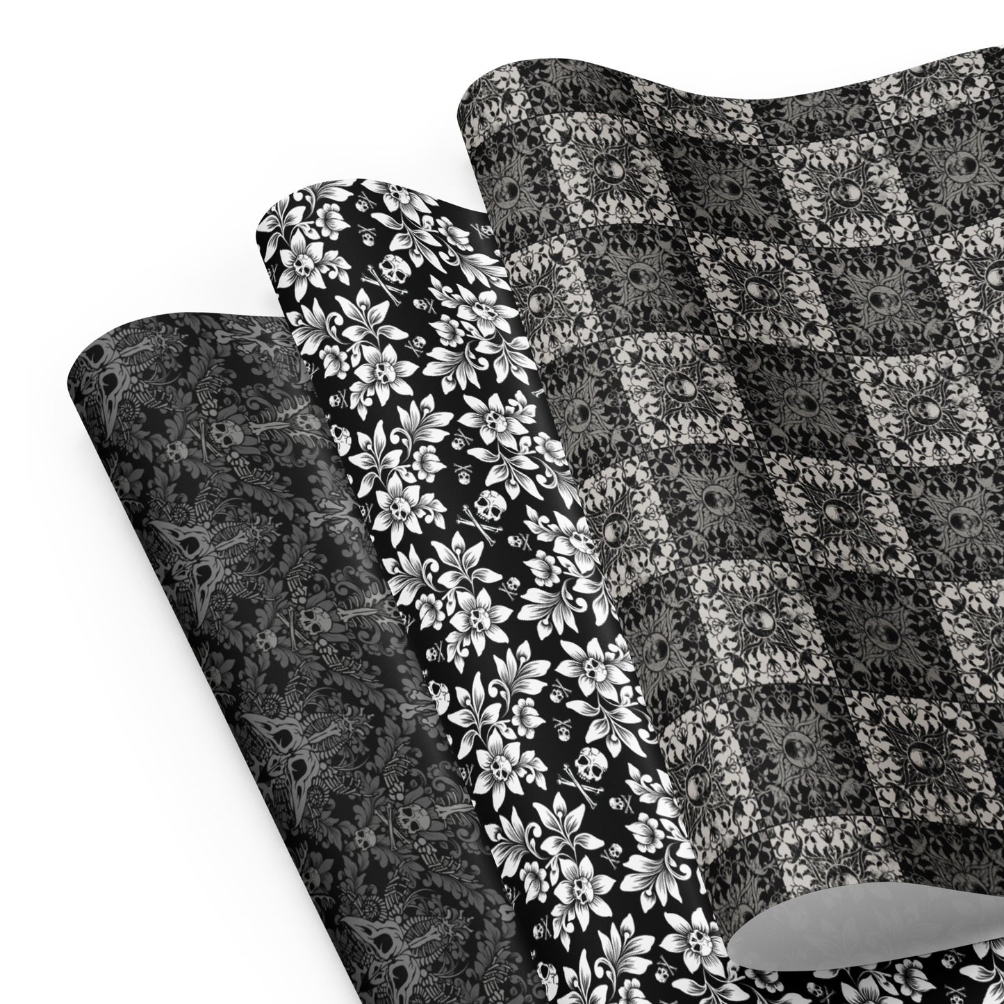 Three gothic black and white gift wrap sheets with skulls on a white background