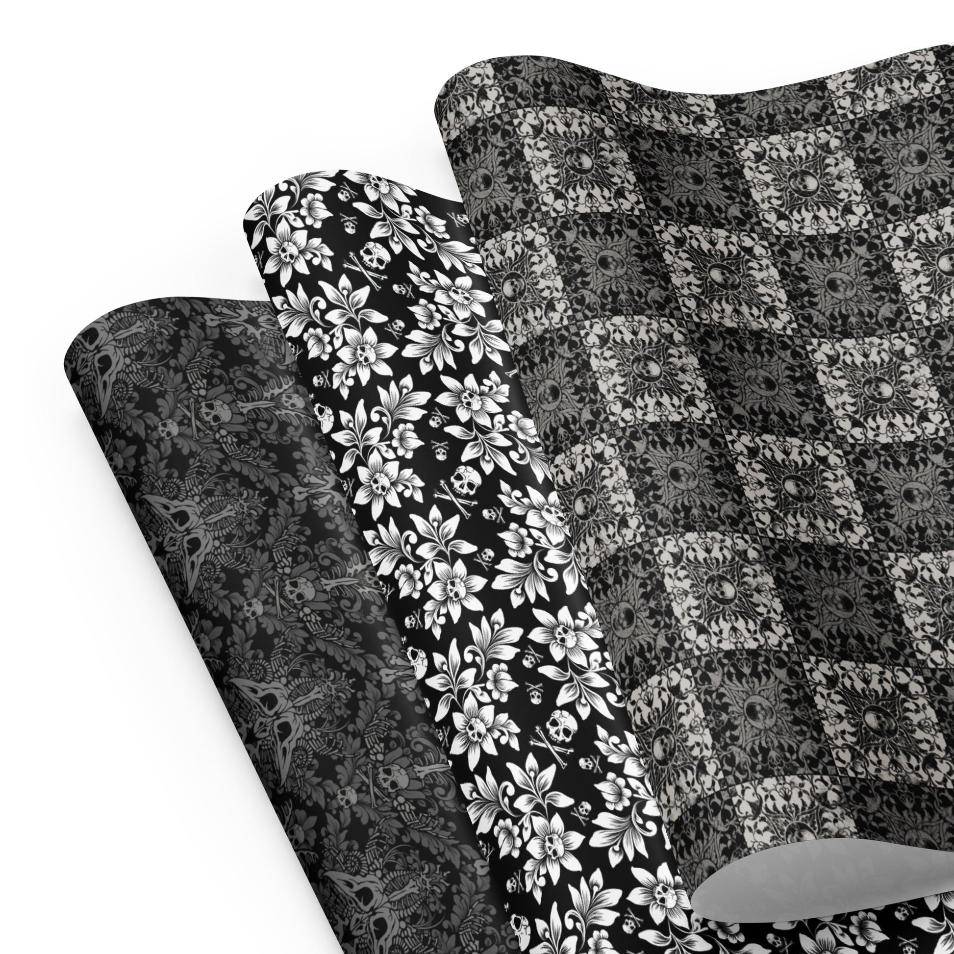 Three gothic black and white gift wrap sheets with skulls on a white background