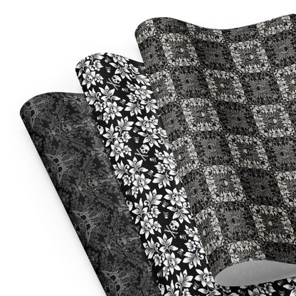 Three gothic black and white gift wrap sheets with skulls on a white background