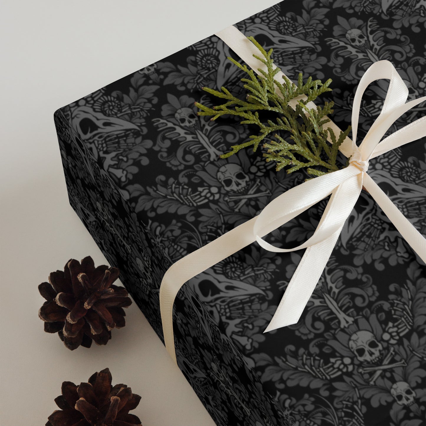 macabre gothic Black patterned gift box with a white ribbon and greenery on a light background