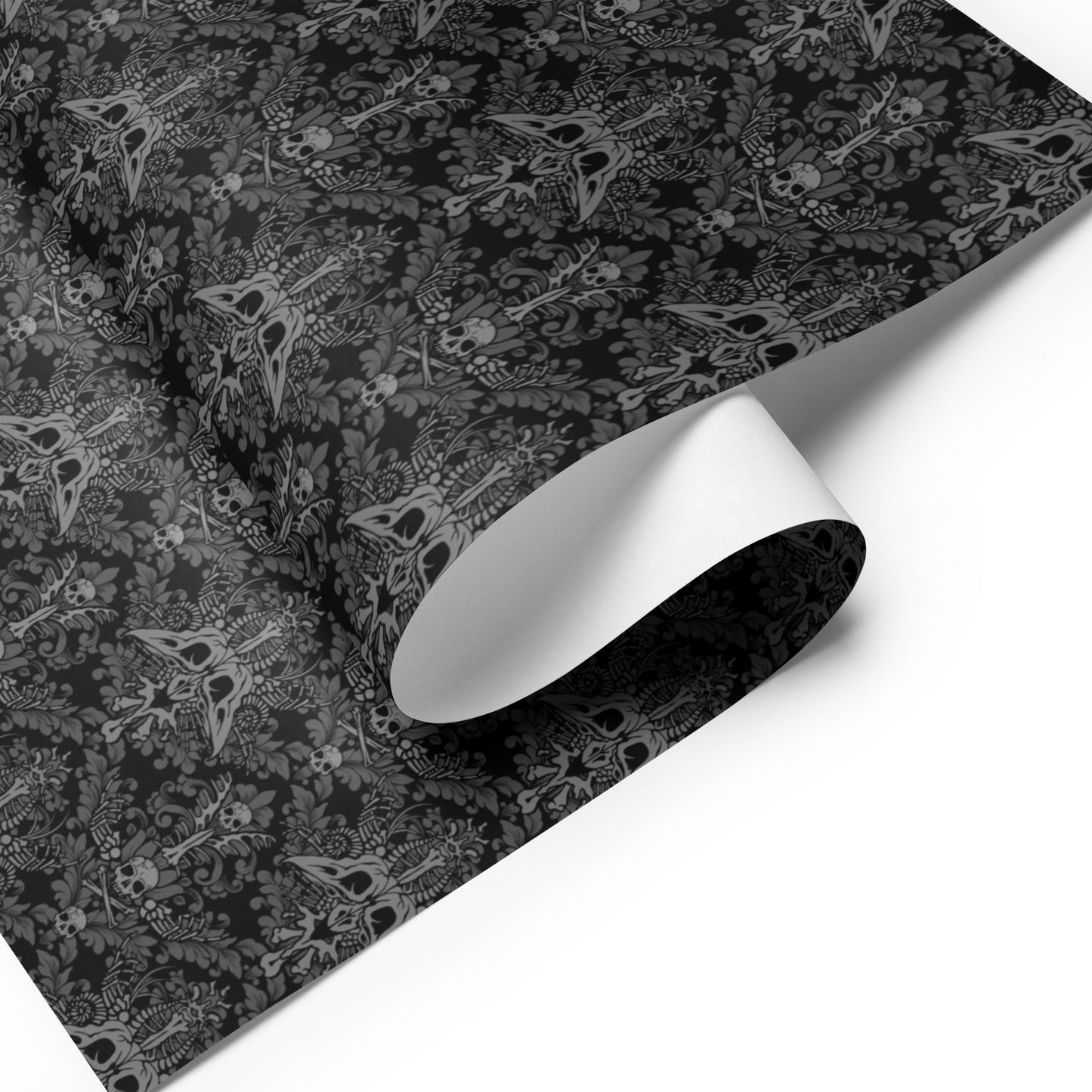 Black and gray baroque damask patterned paper with a roll of white paper on a white background