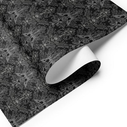 Black and gray baroque damask patterned paper with a roll of white paper on a white background