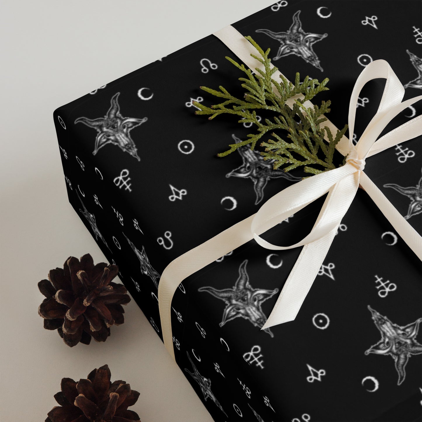Gift box wrapped in black paper with satanic baphomet patterns, tied with a white ribbon, on a light background.