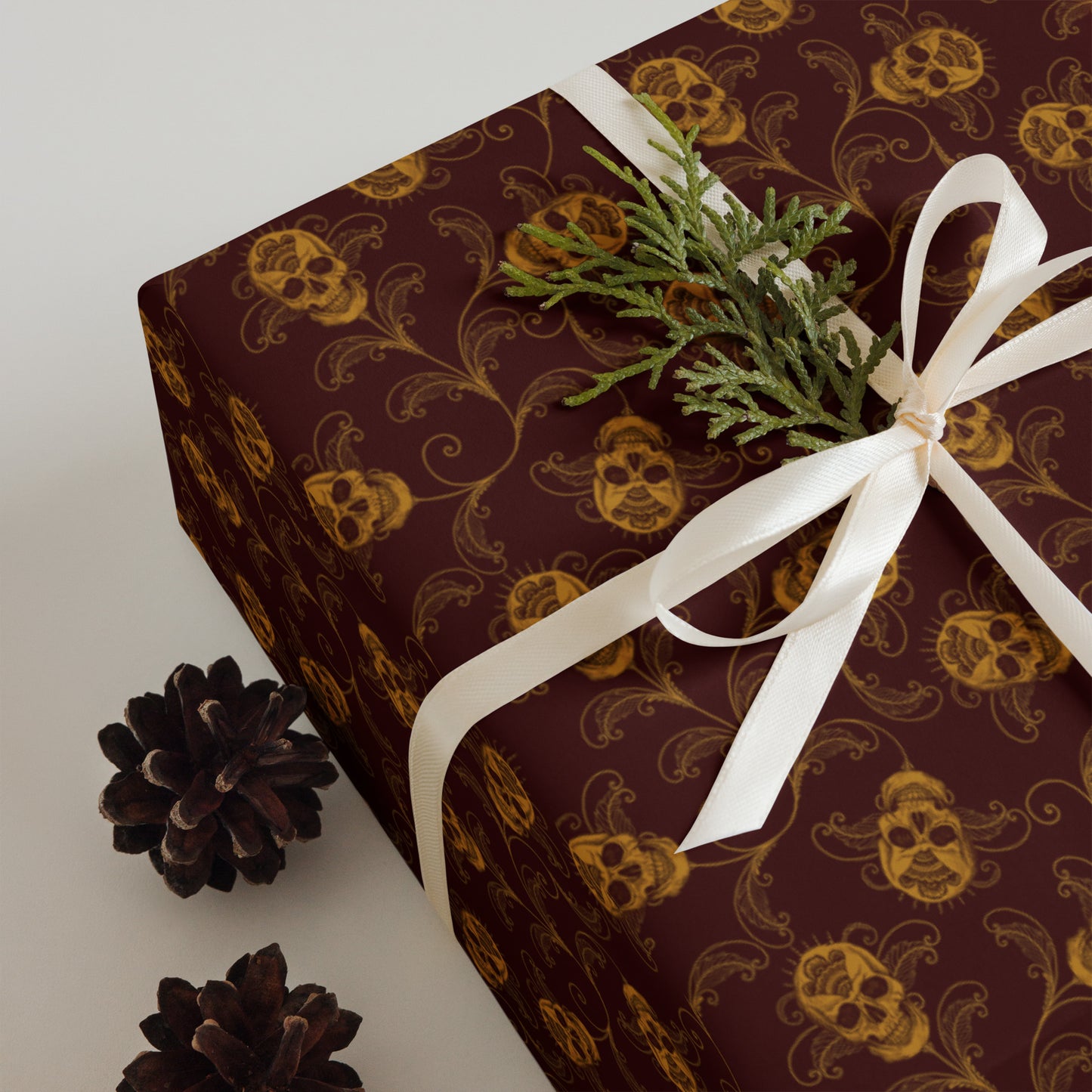 Gift box with decorative red and gold skull pattern and white ribbon on a light background