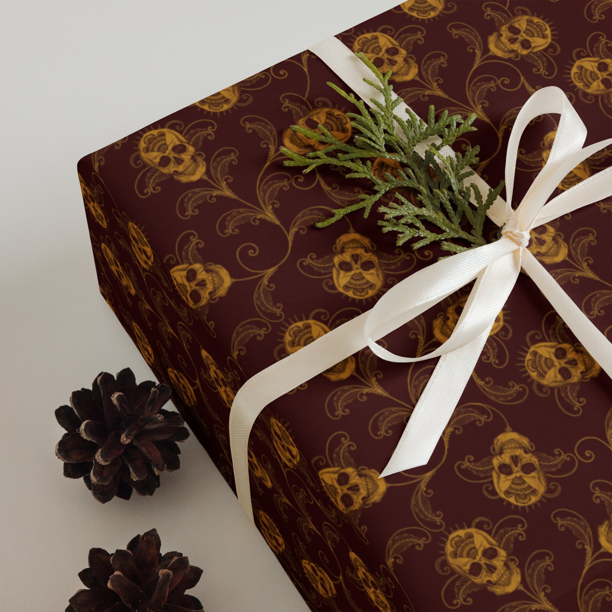 Gift box with decorative red and gold skull pattern and white ribbon on a light background